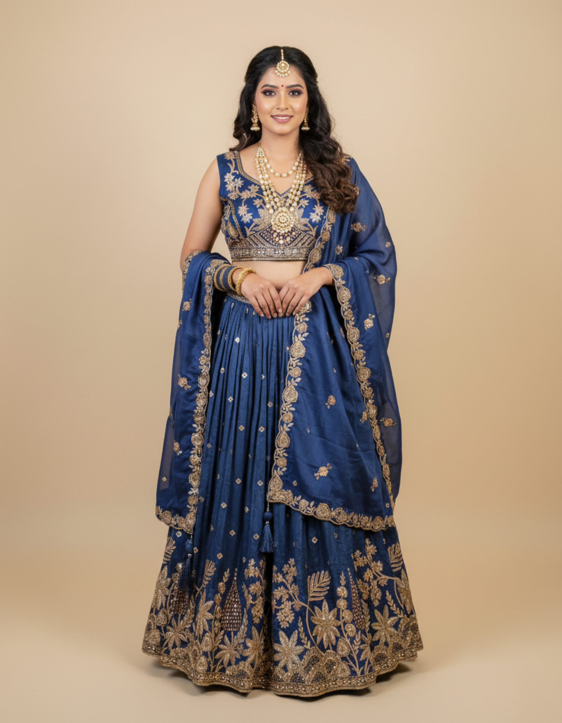 Woman wearing a blue embroidered traditional outfit on a beige background